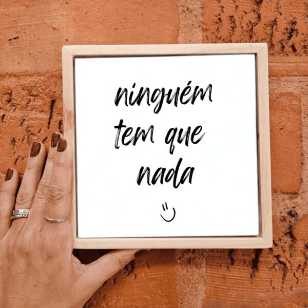Mão segurando o azulejo decorativo Ninguém Tem Que Nada
