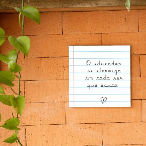 Azulejo decorativo O Educador se Eterniza com estampa de caderno, pendurado na parede de tijolos