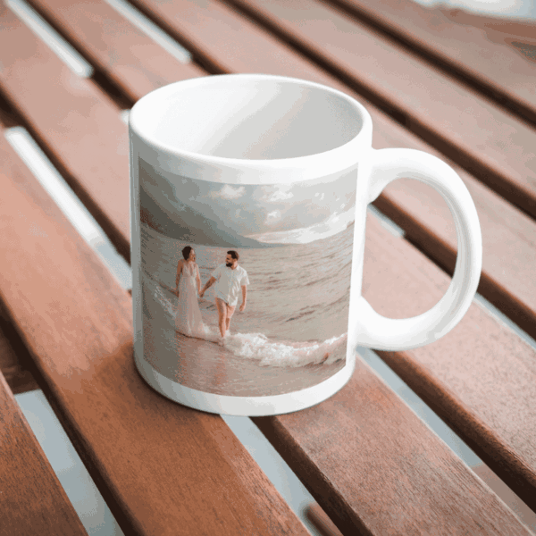 Caneca personalizada com foto de casal caminhando na praia, sobre mesa de madeira