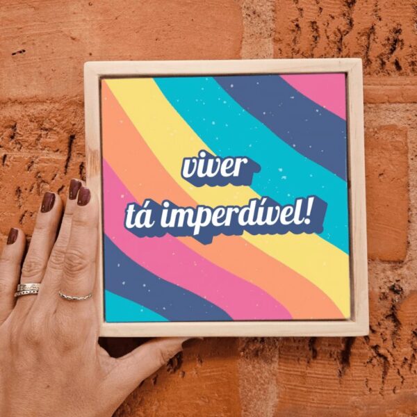 Mão segurando o azulejo decorativo Viver Tá Imperdível