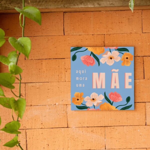 Azulejo floral azul Aqui Mora Uma Mãe, pendurado na parede de tijolos