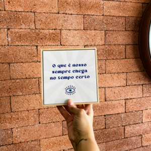 Mão segurando o azulejo decorativo O Que É Nosso Sempre Chega no Tempo Certo