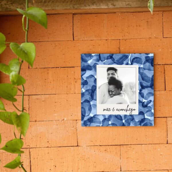 Azulejo personalizado Mãe é Aconchego com foto e fundo floral azul, pendurado na parede de tijolos