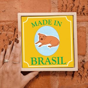 Mão segurando o azulejo decorativo Cachorro Caramelo Made in Brasil