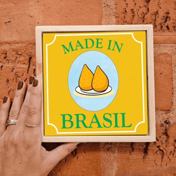 Mão segurando o azulejo decorativo Coxinha Made in Brasil