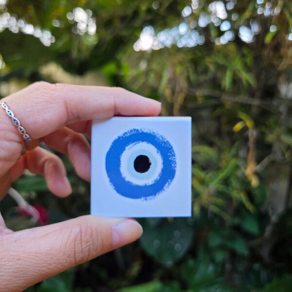 Mão segurando o mini azulejo com ímã de olho grego