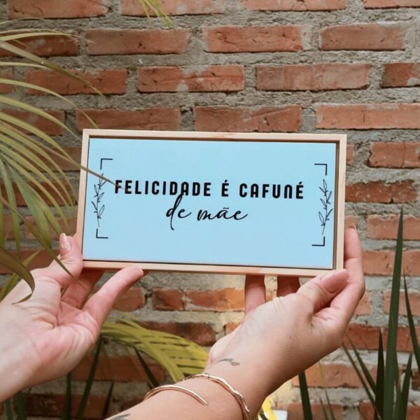 Mãos segurando a plaquinha Felicidade é cafuné de mãe